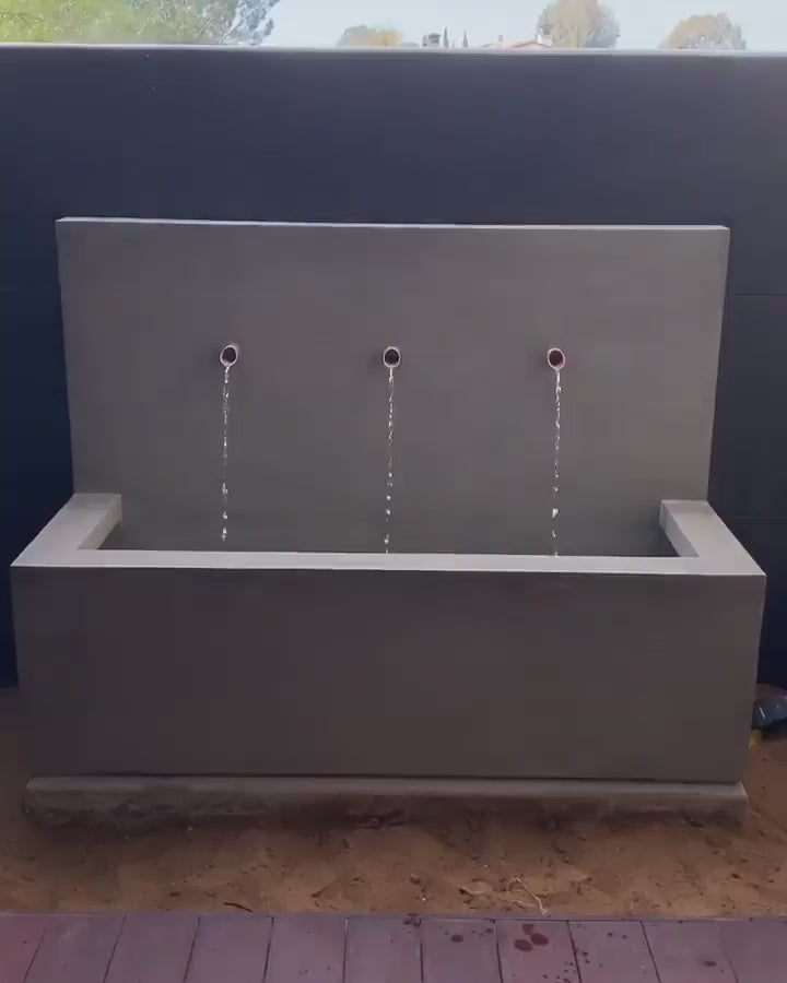 Long Beach Wall Outdoor Fountain mounted on a stone wall in a garden patio