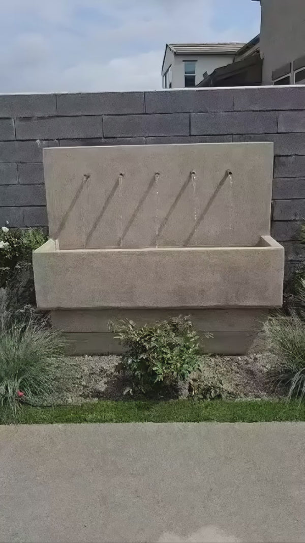 Penta Wall Fountain mounted on a textured stone wall in a modern outdoor space